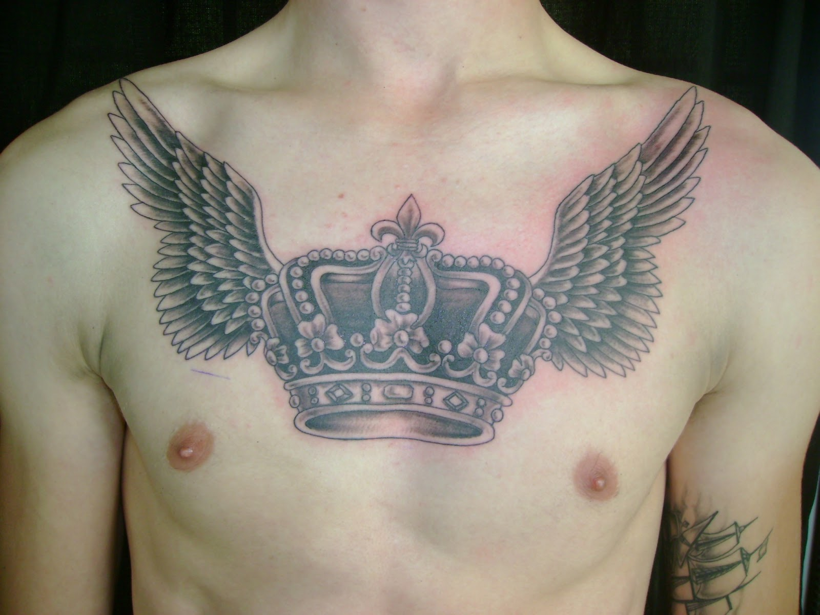 Grey Ink Winged Crown Tattoo On Man Chest inside sizing 1600 X 1200